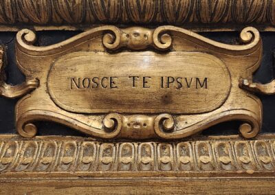 Ornate wooden plaque with Latin inscription 'NOSCE TE IPSUM'.