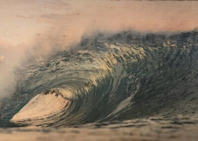A large ocean wave curling under a misty sky at sunset.