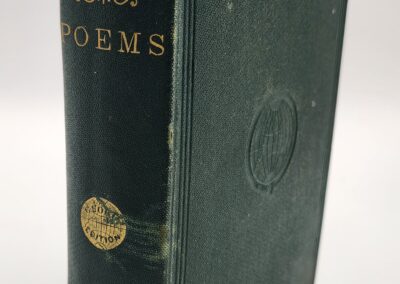 Close-up of a vintage green book titled 'Poems' with embossed details and gold lettering.