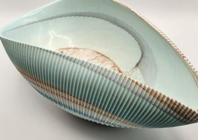 A curved ceramic sculpture with blue and green striped patterns.