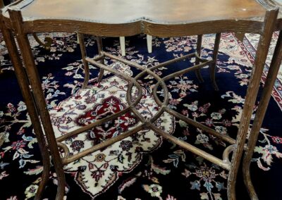 Antique wooden side table with curved legs and scalloped edges on a patterned rug.
