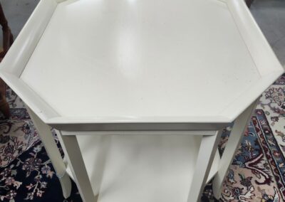 White hexagonal side table with a lower shelf on a patterned rug.