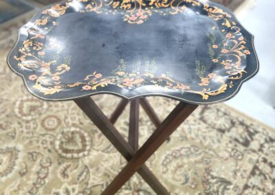 Ornate vintage folding tray table with floral design and scalloped edges.