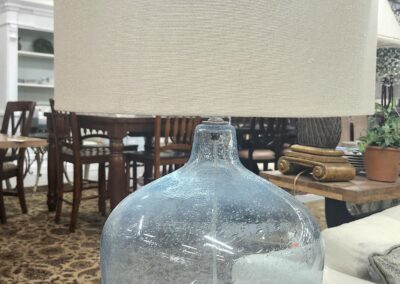Large clear glass bottle with a wide neck on a table in a cozy room.