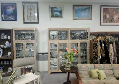 Cozy living room with vintage windows, framed art, and fresh flowers on a wooden table.