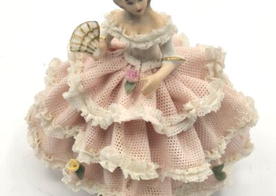 Porcelain figurine of a girl in a layered pink dress holding a basket of flowers.