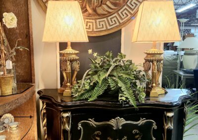 Elegant black cabinet with gold accents and decorative lamps.