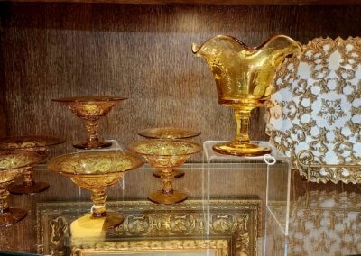 Golden glassware displayed on a reflective surface against a wooden background.