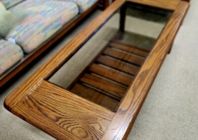 Wooden coffee table with glass top and slatted shelf underneath.