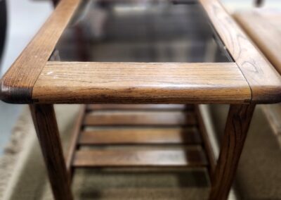 Wooden side table with a glass top and lower shelf.
