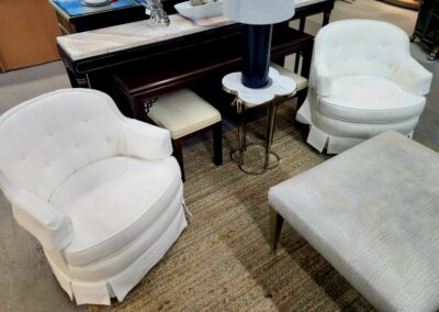 Cozy white upholstered chairs and ottoman arranged around a small side table.