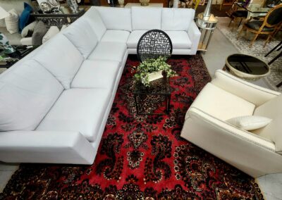 Modern white sectional sofa and armchair on an intricate red Persian rug.
