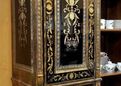 Ornate antique wooden cabinet with intricate gold detailing and floral patterns.