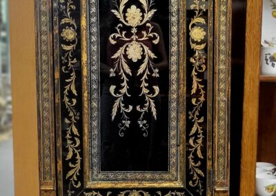 Ornate wooden cabinet door with intricate floral designs and gold accents.