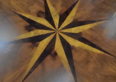 A wooden star-shaped compass rose inlaid in a polished floor.