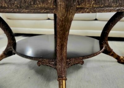 Close-up of ornate wooden table legs with brass claw feet on a light carpet.