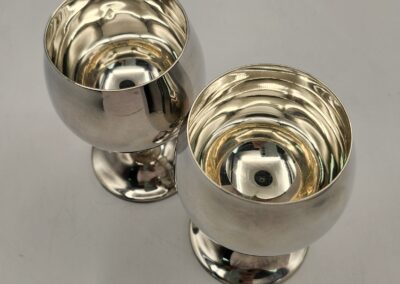 Two polished silver goblets with a reflective surface on a gray background.
