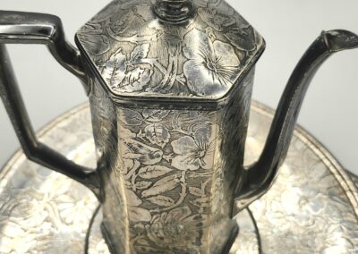 Intricately engraved silver teapot with hexagonal shape and matching tray.