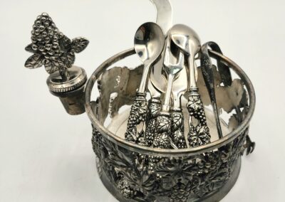 Ornate silver condiment holder with spoons and a butterfly handle.