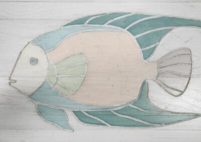 A pastel-colored fish artwork on a wooden surface.