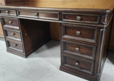 Close-up of a classic wooden desk with drawers and brass handles.