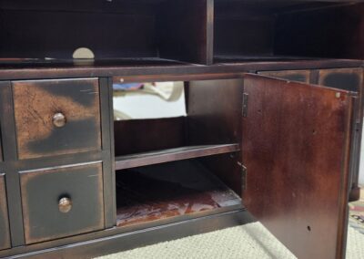 An antique wooden cabinet with drawers and an open door revealing shelves.