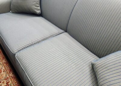 A modern gray fabric sofa with two matching cushions on a patterned carpet.