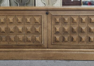 Wooden cabinet with intricately carved square patterns on the doors.