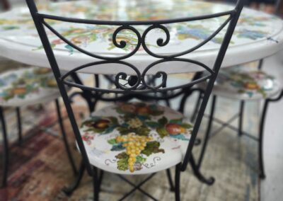 Decorative iron chair with floral cushion at a glass table.