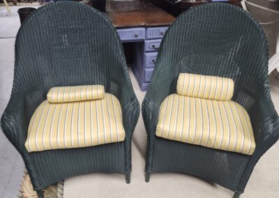 Two green wicker chairs with yellow striped cushions.