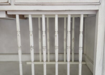A white metal gate with vertical bars and a latch on the side.