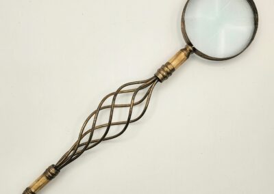 Antique magnifying glass with an ornate twisted metal handle.