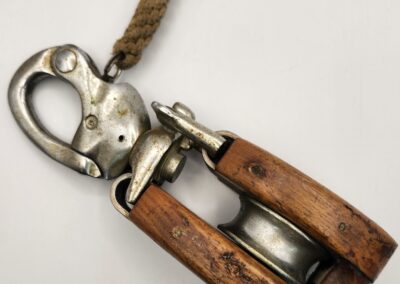 Vintage wooden pulley block with metal hooks and rope.