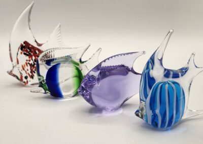 Four colorful glass fish sculptures arranged in a row on a white surface.