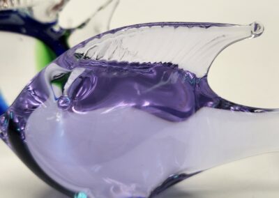 A delicate glass fish sculpture in shades of purple and blue.