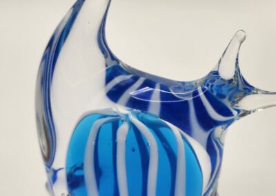 A blue and white striped glass fish sculpture with a clear fin.