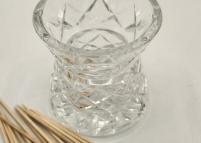 Clear glass candle holder with wooden matches beside it.