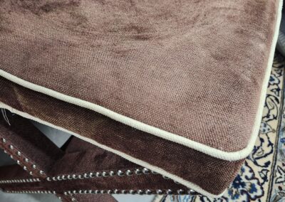 Brown cushioned chair seat with white piping detail.