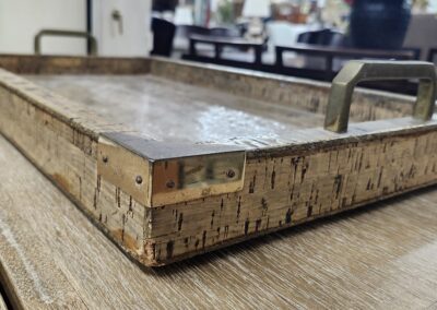 Rustic cork tray with metal handles on a wooden table.