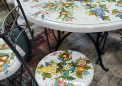 Colorful floral patterns on round table and stools with black metal legs.