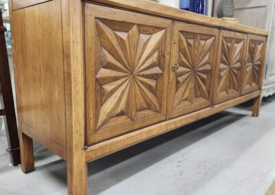 Vintage wooden cabinet with carved geometric patterns on the doors.