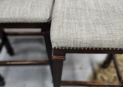 Close-up of two cushioned stools with textured fabric seats and dark wooden legs.