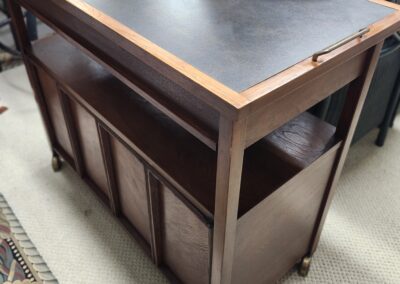 Wooden bar cart with a black top and storage shelves.