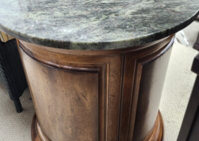 Round wooden cabinet with marble top.