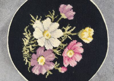 Embroidered floral bouquet on a round black fabric patch.