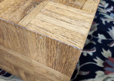 Close-up of a wooden block with a parquet pattern on a floral carpet.
