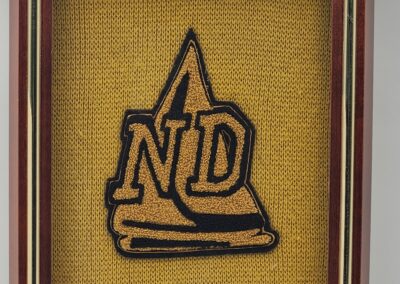 Framed Notre Dame logo on a yellow background.