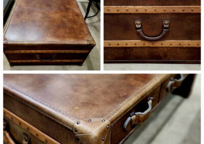 Vintage brown leather suitcase with metal studs and handles.