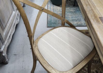 Wooden chair with a cushioned seat in a rustic setting.