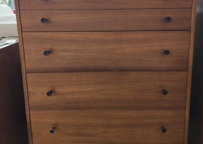 Mid-century modern wooden dresser with four drawers and round knobs.
